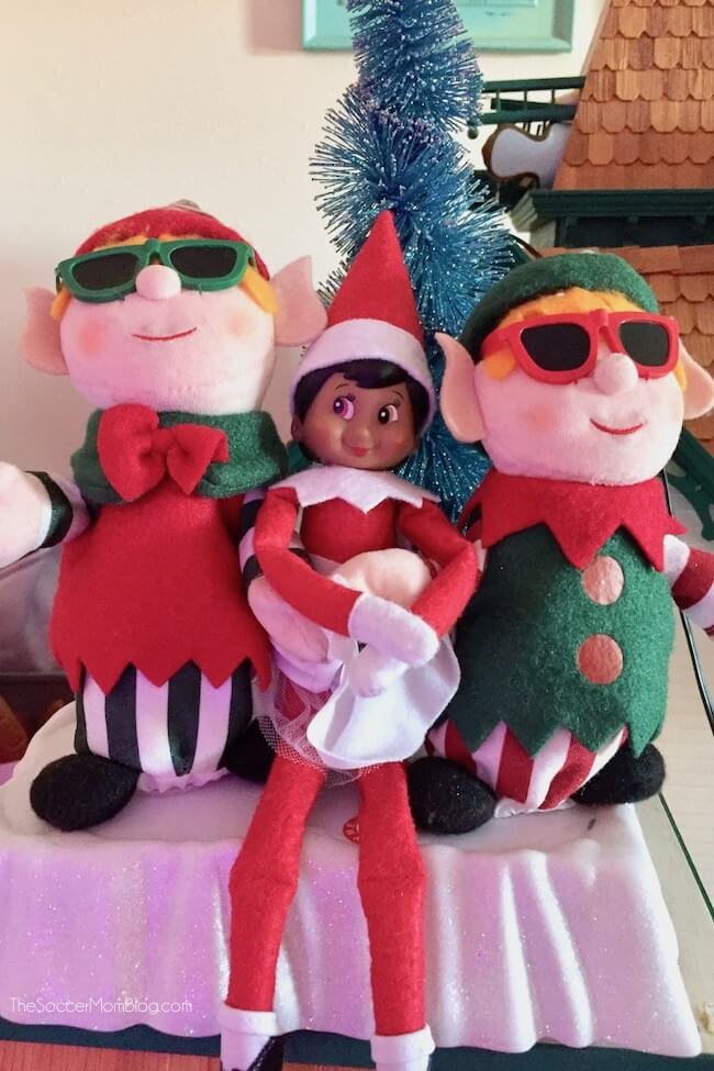 Elf on the Shelf sitting between two toy elves