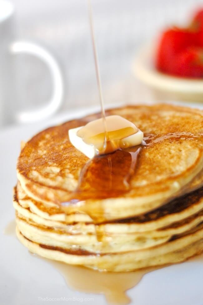 Pouring syrup over a stack of gluten free pancakes