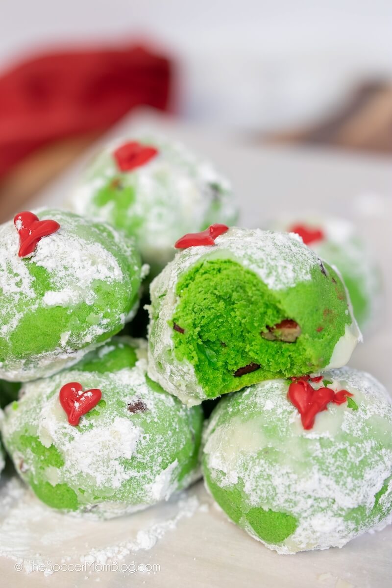 green snowball cookies with red heart decoration aka Grinch Cookies.