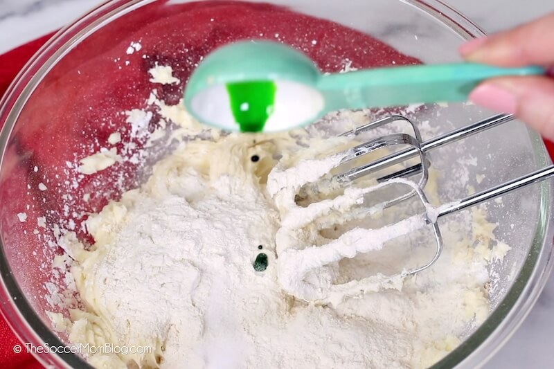 adding green food coloring to cookie dough.