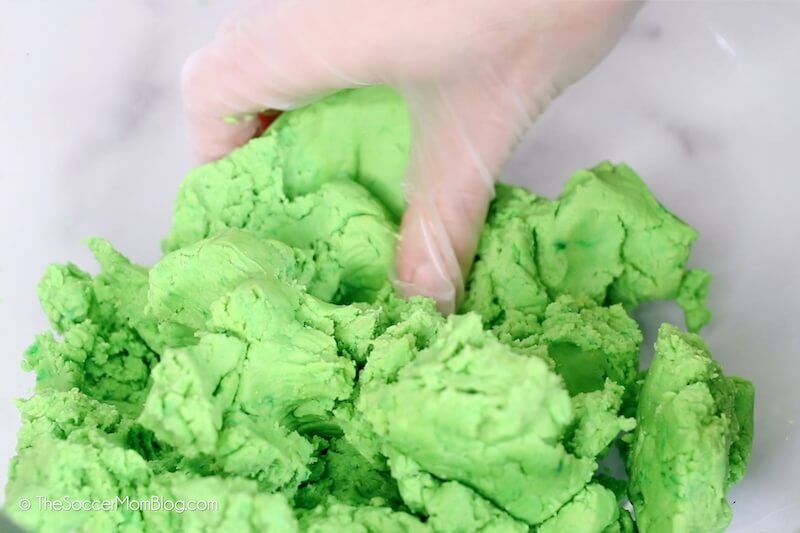 mixing green cookie dough by hand.