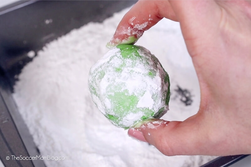 ball of green Christmas cookie dough coated in powdered sugar