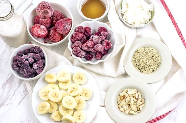 Berries, bananas, nuts, and seeds in bowls to make smoothies