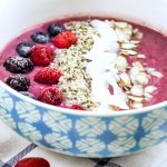 a purple smoothie bowl topped with fresh berries